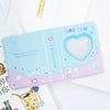 A light blue hollow photo card binder with a heart-shaped clear window and decorative text like you and lucky