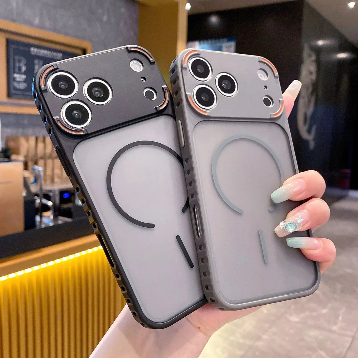 A hand holds a gray frosted magnetic silicone case for an iPhone, displaying the back and camera module.