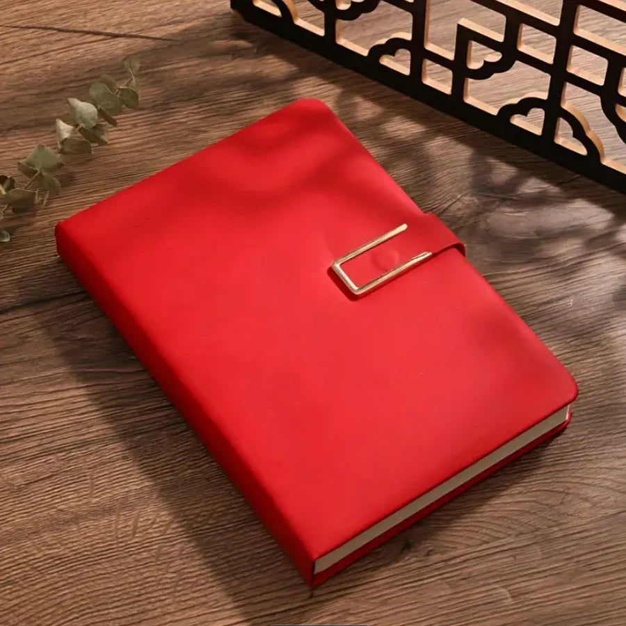 A red A5 retro leather notebook lying on a wooden surface next to a decorative wooden shelf.