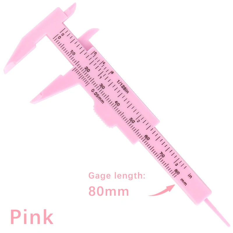 Pink precision eyebrow measuring caliper showing a scale marked in millimeters and inches.