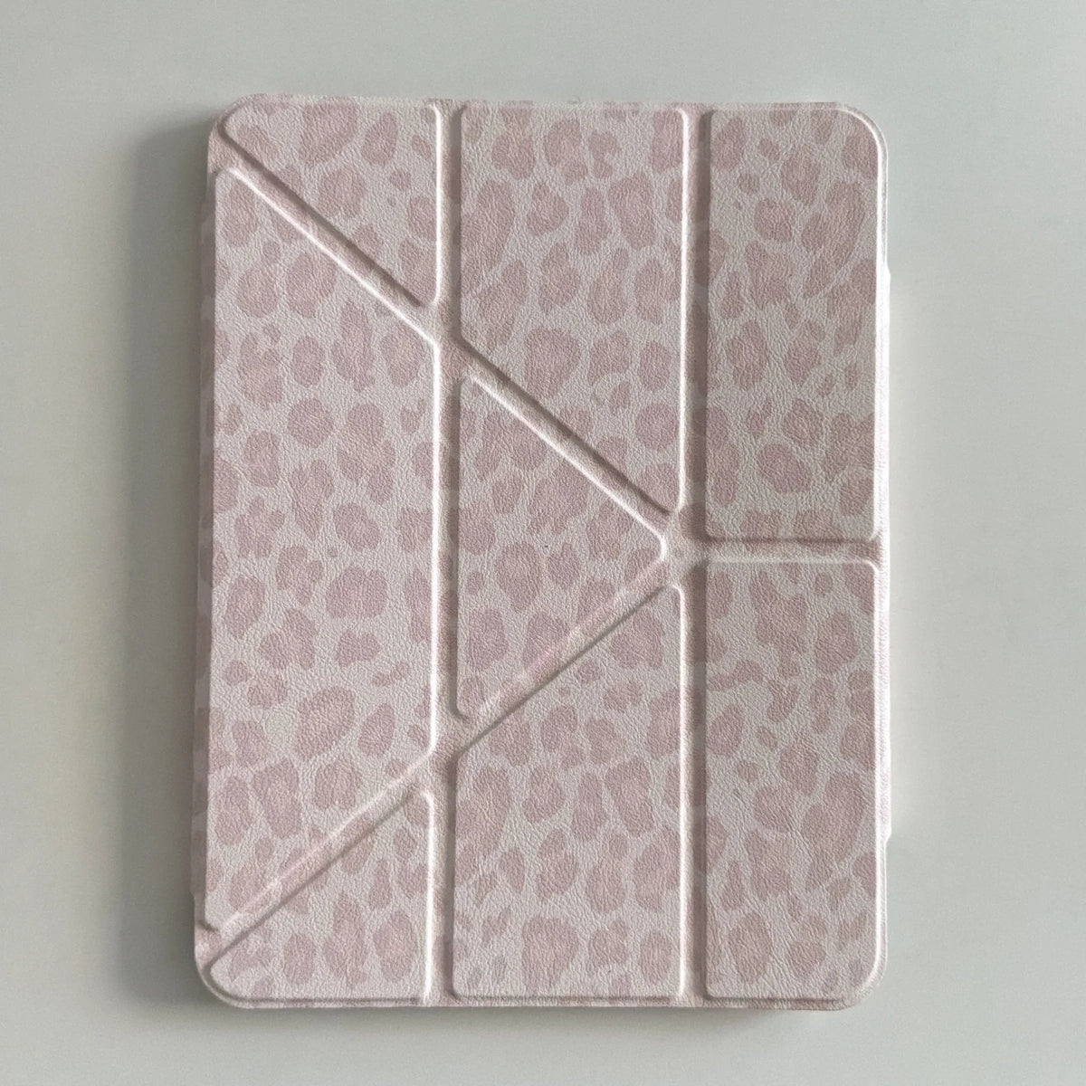 A pink leopard print leather case designed for an iPad, featuring a textured, segmented design.