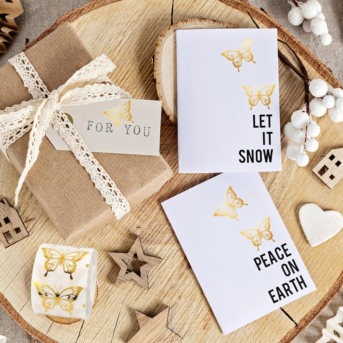 Golden butterfly decorative stickers on a white card next to a gift box and natural wood background