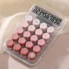 A clear plastic calculator with pink buttons and a digital display showing the number 1234567890.
