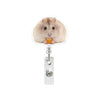 A fluffy light brown hamster is holding a piece of orange food, featured on an acrylic badge reel.