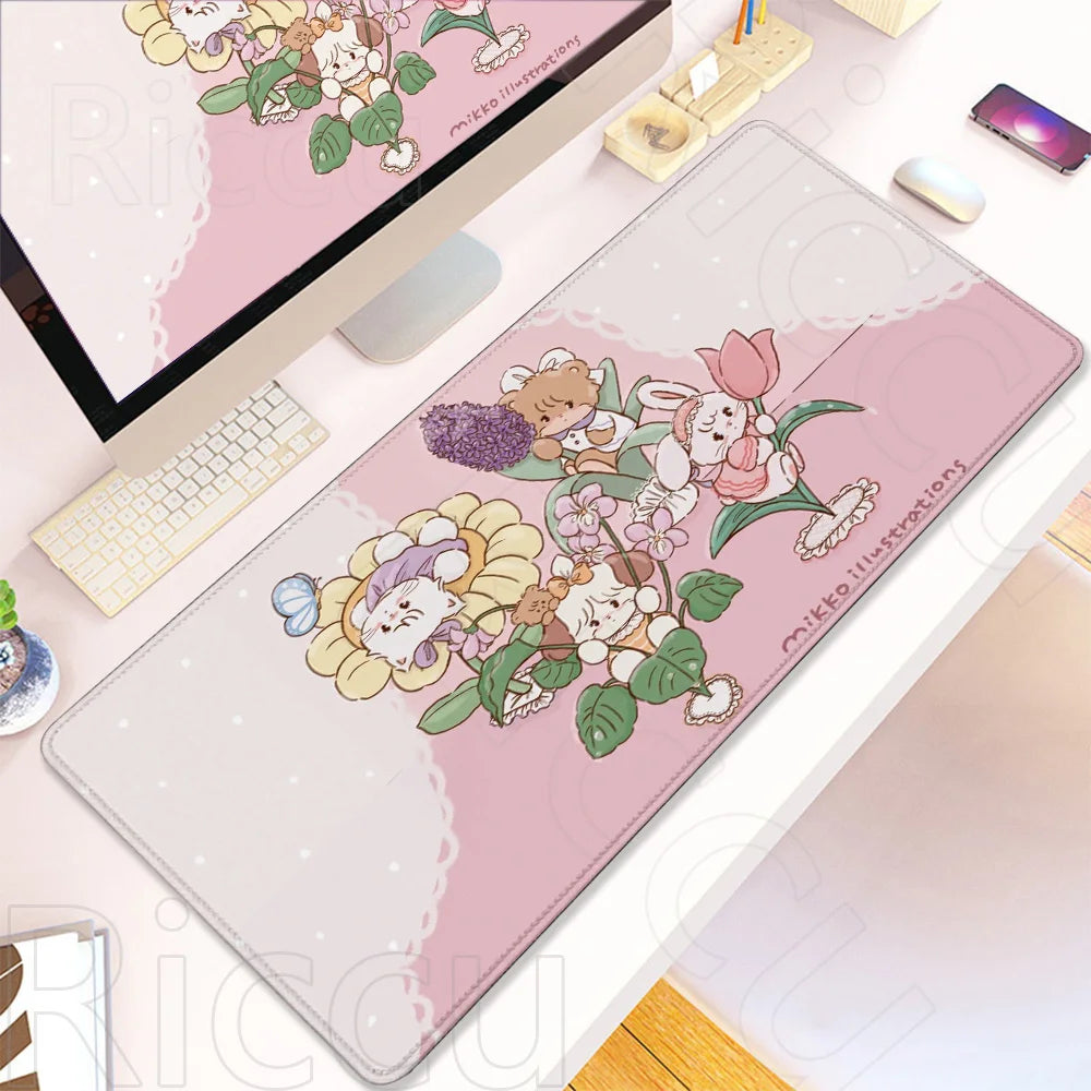 A pink cartoon gaming desk mat featuring cute woodland animals and flowers, displayed next to a laptop.