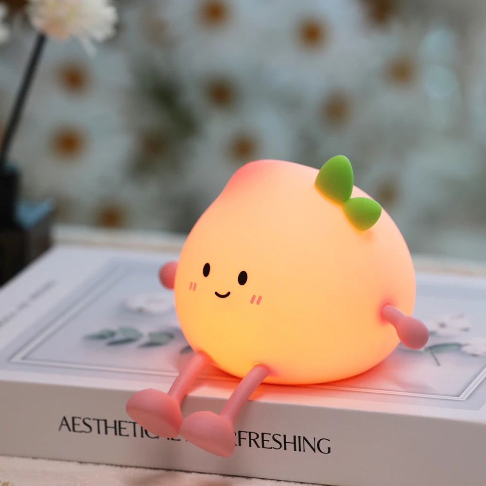 A peach-shaped rechargeable night light with a smiling face rests on a white box.