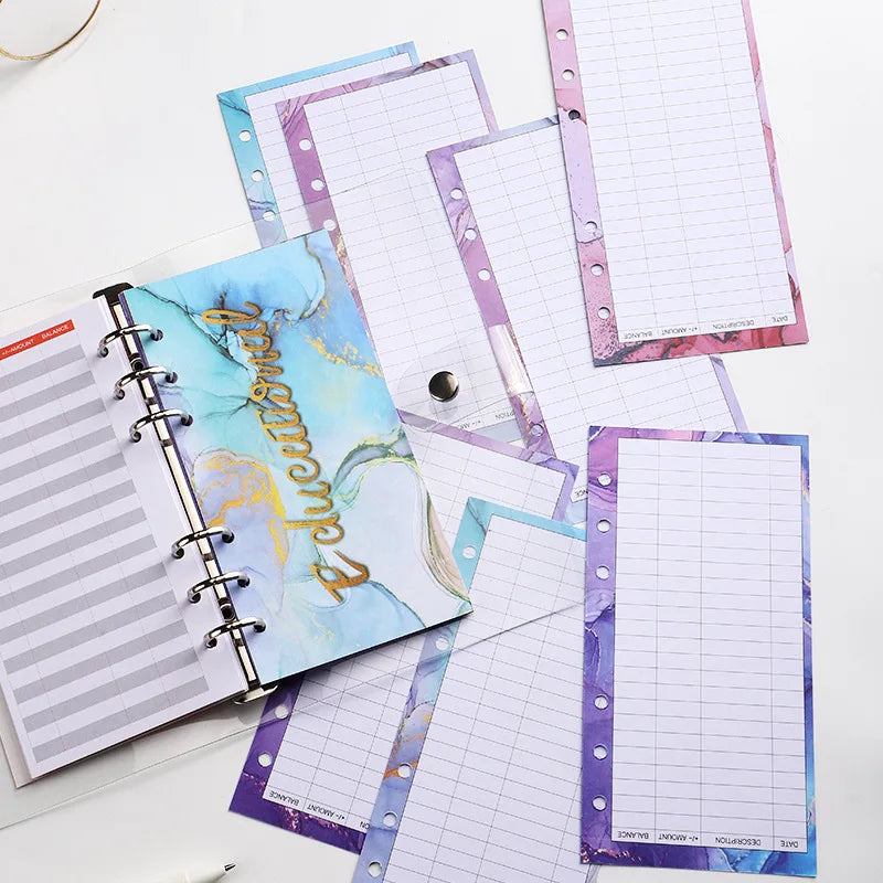 A stack of A6 budget planner binders featuring purple and blue patterned paper with spiral binding.