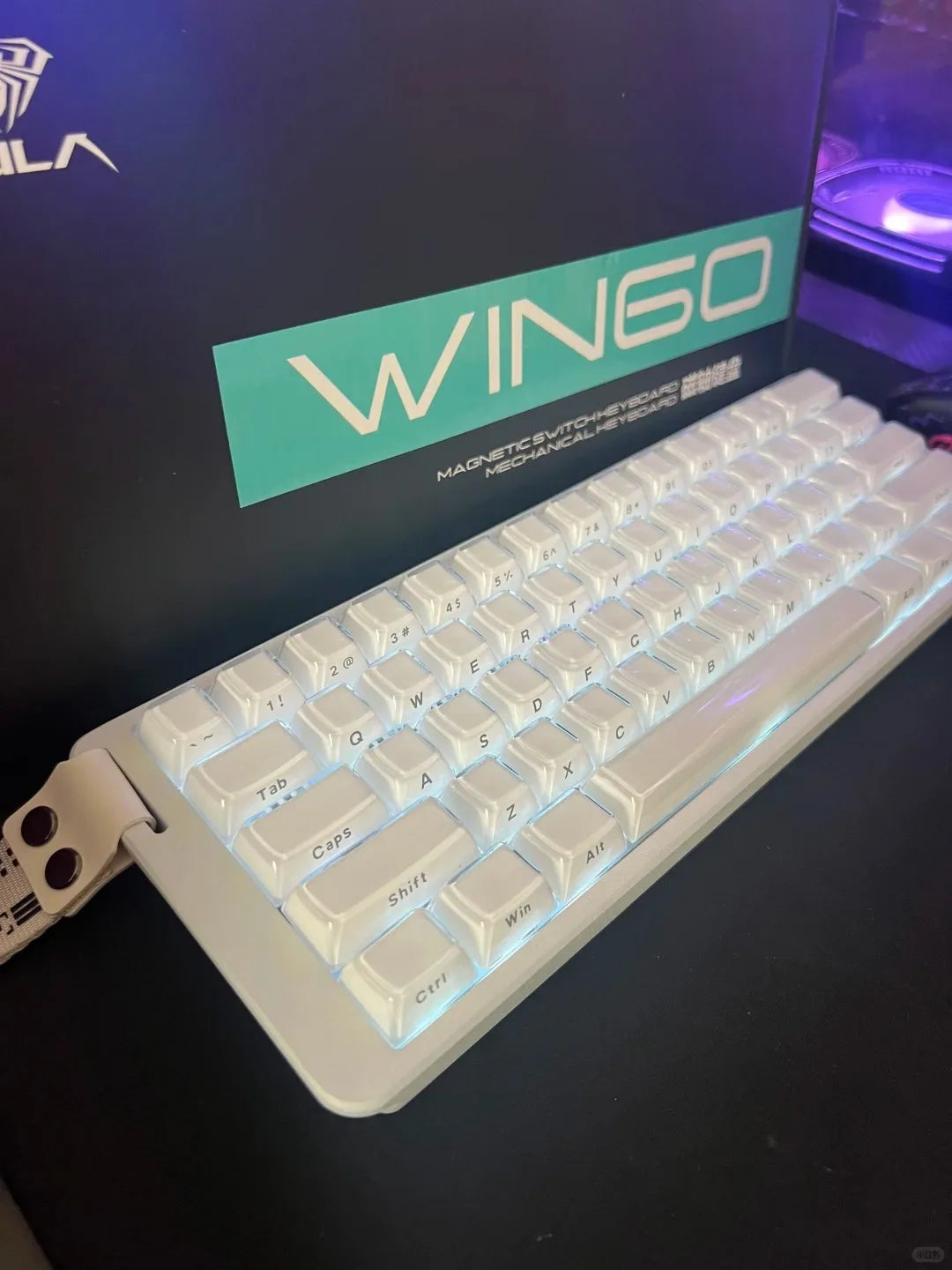 A white wired compact gaming keyboard with blue backlighting is shown in a box.