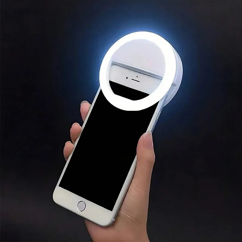 يد تمسك بهاتف ذكي مضاء بضوء حلقة LED دائري، يلقي توهجًا ساطعًا على الجهاز.