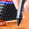 A close-up view of a stack of black fine point pens and a hand writing with one of the pens.