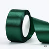 A roll of dark emerald green satin ribbon used for gift wrapping or DIY crafts.