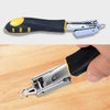 A hand holds a heavy duty manual multi-use staple gun with a black and yellow handle and silver stapler head.