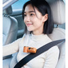 A woman is holding an orange portable rechargeable handheld cooling fan while seated in a car seat.