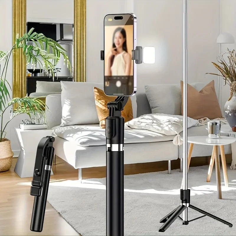 A black extendable selfie stick tripod with a wireless remote is displayed in a bright living room setting.