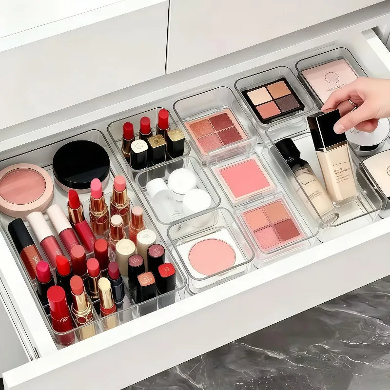 Clear acrylic drawer organizer set containing various makeup products like lipsticks and palettes.