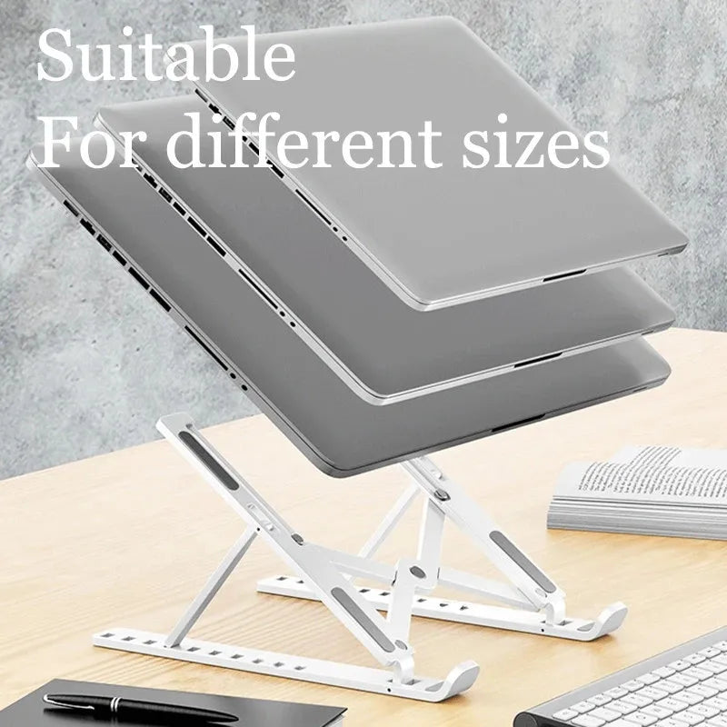 A silver foldable adjustable laptop stand is shown with a laptop resting on it, next to a keyboard and pen.