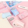 A collection of pink, blue, and white cartoon mini staplers and related stationery items displayed on a light pink background