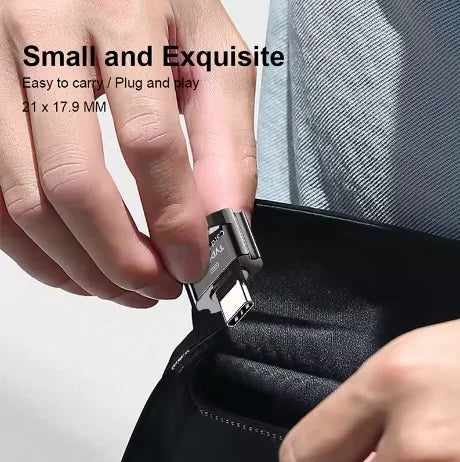 A hand is inserting a small Type-C to Micro-SD card reader into a black sleeve or case.