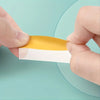 A hand is holding a stack of orange and white index tags against a light teal background.