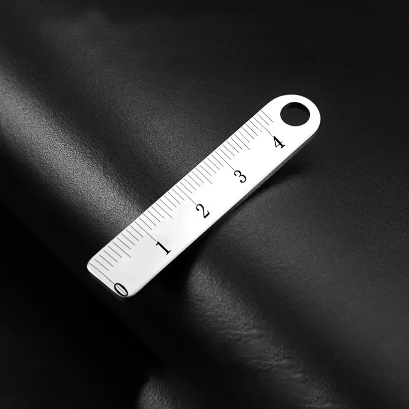 A stainless steel mini ruler with markings is shown against a dark background.