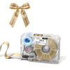 A clear label maker device with a ribbon bow and a roll of gold ink is shown on a white background.