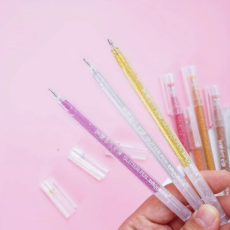 A hand holds a set of 12 glitter gel pens in various vibrant colors against a pink background.