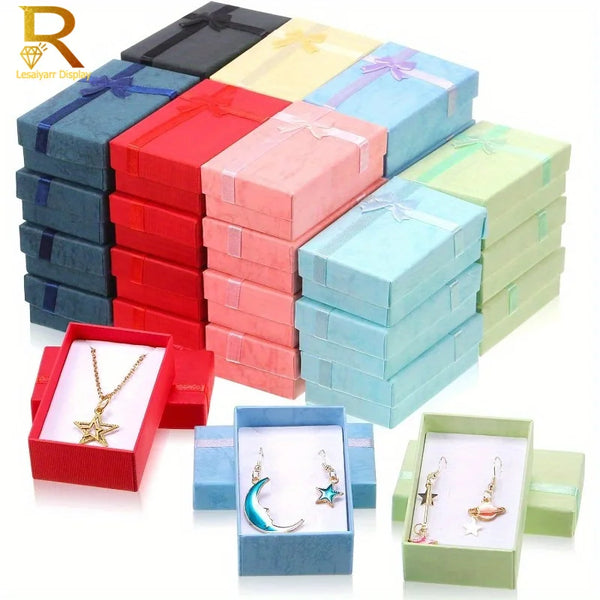A stack of 24 colorful jewelry gift boxes in various shades of pink, blue, and green with velvet interiors.