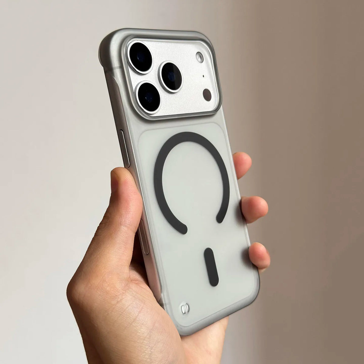 A hand holds a slim magnetic phone case for iPhone Magsafe with a clear back and camera module.