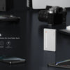Weiße portable NVMe SSD-Gehäuse auf dunkler Oberfläche mit elektronischen Geräten