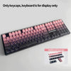 A close-up view of a black mechanical keyboard featuring pink and purple PBT keycaps, with additional keycaps displayed below