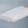 A white self-sealing waterproof shipping bag is being held and water is dripping from it against a gray background.