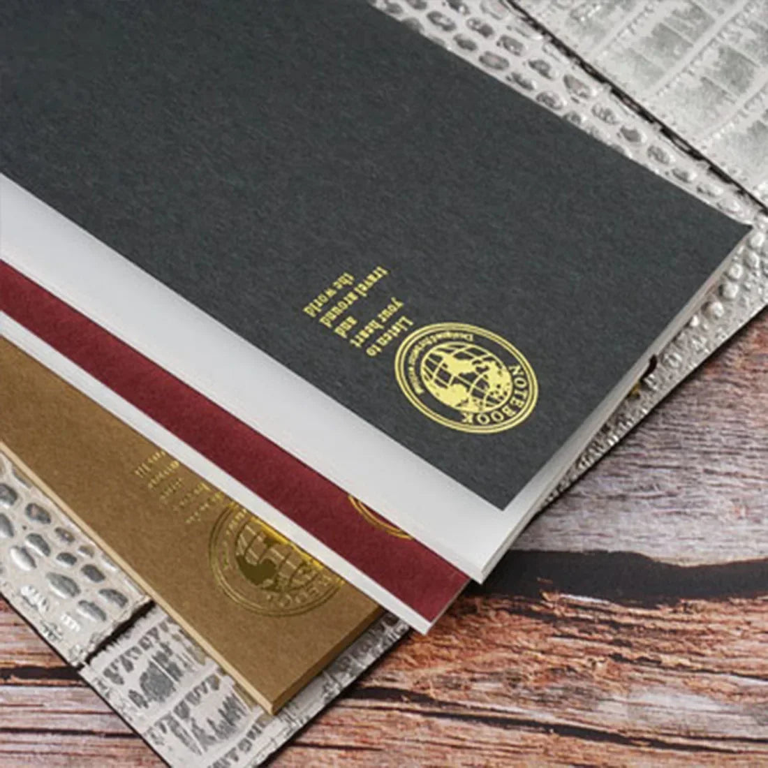 A close-up of retro gold foil inserts for notebooks and journals stacked on a wooden surface.
