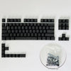 Un set de teclas de contorno degradado negras para un teclado mecánico, mostrado junto a una bolsa de plástico.