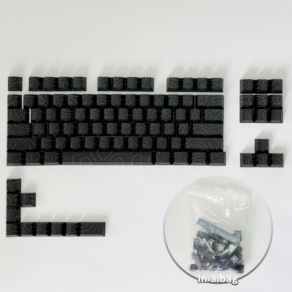 Un set de teclas de contorno degradado negras para un teclado mecánico, mostrado junto a una bolsa de plástico.