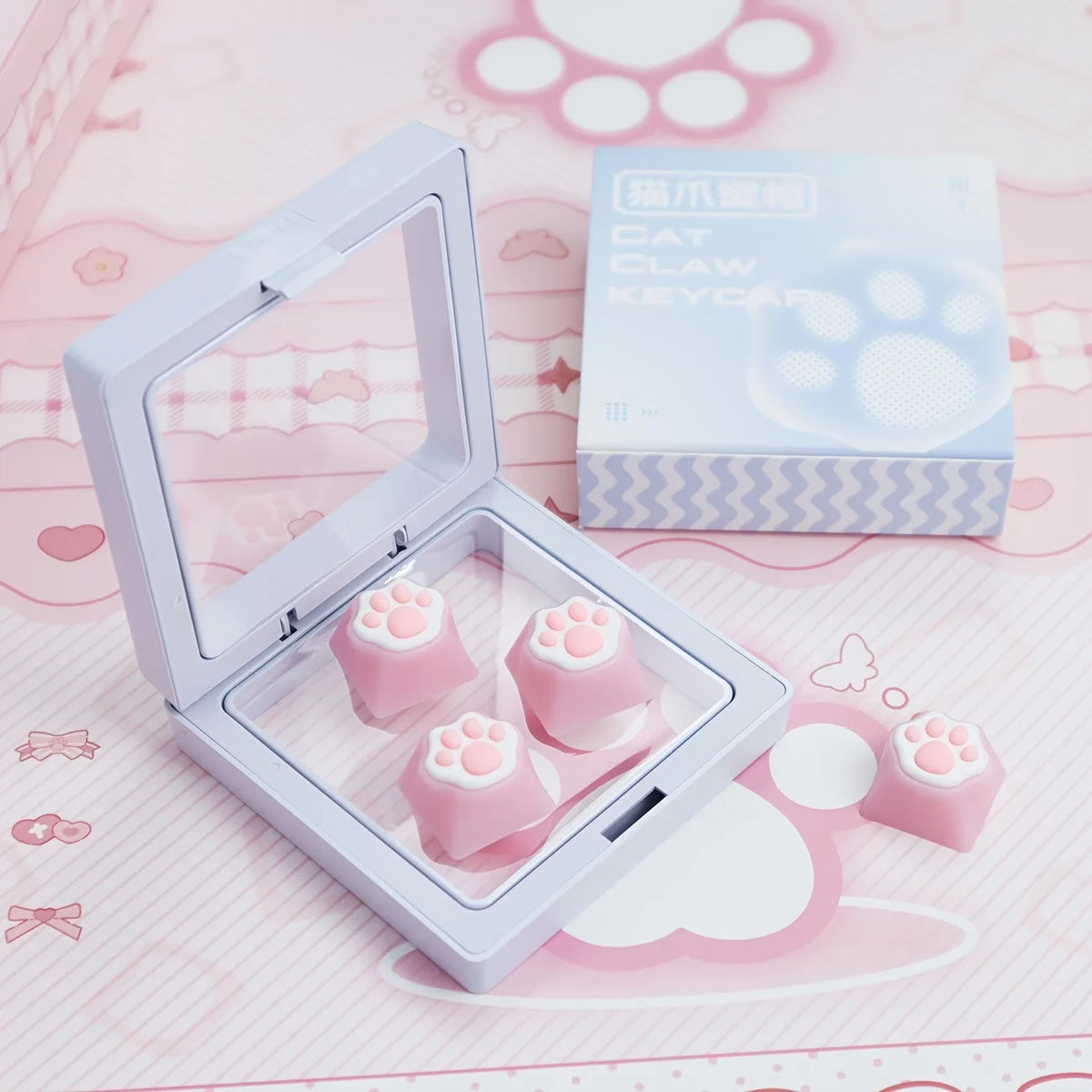 A clear plastic case holds pink cat paw and heart shaped keycaps for MX switches on a pink background.