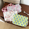 A collection of floral quilted ladies clutch purses in various colors and patterns are displayed on a wooden surface.