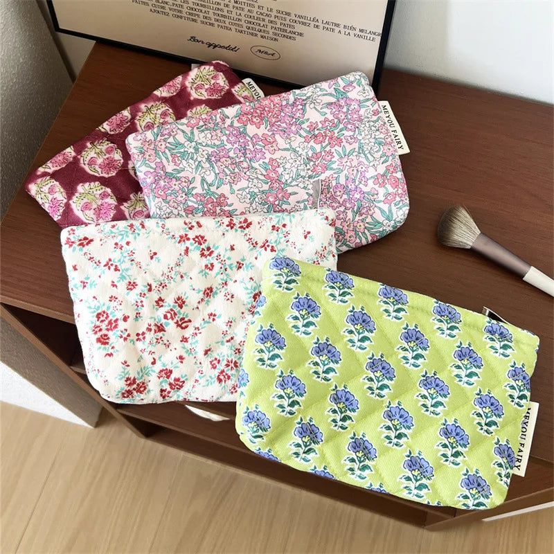 A collection of floral quilted ladies clutch purses in various colors and patterns are displayed on a wooden surface.