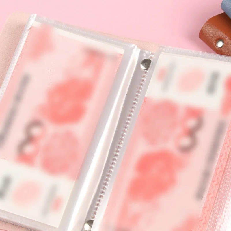 A close-up of a reusable envelope money saving challenge binder with pink pages and a clear plastic cover.