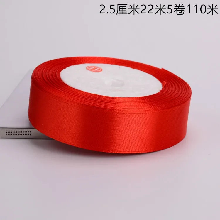 A roll of red satin ribbon with white batting, packaged for crafts and decor.