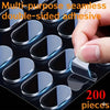 A hand is applying multi-purpose seamless double-sided adhesive pieces onto a dark surface.