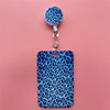 A blue leopard print retractable card holder clip with a circular badge holder attached.