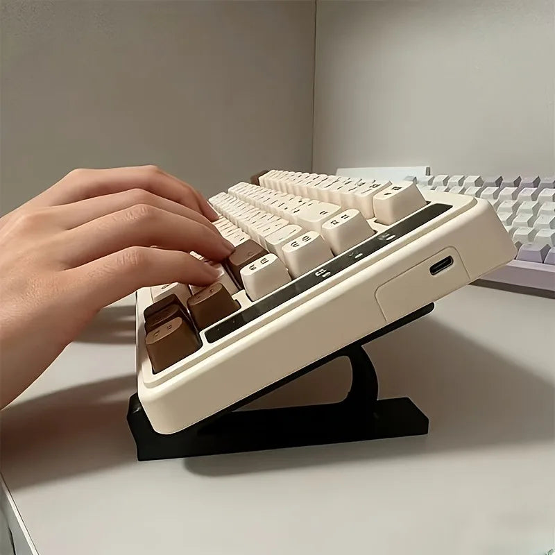 A hand is placing keys onto an ergonomic keyboard riser stand with anti-slip base.