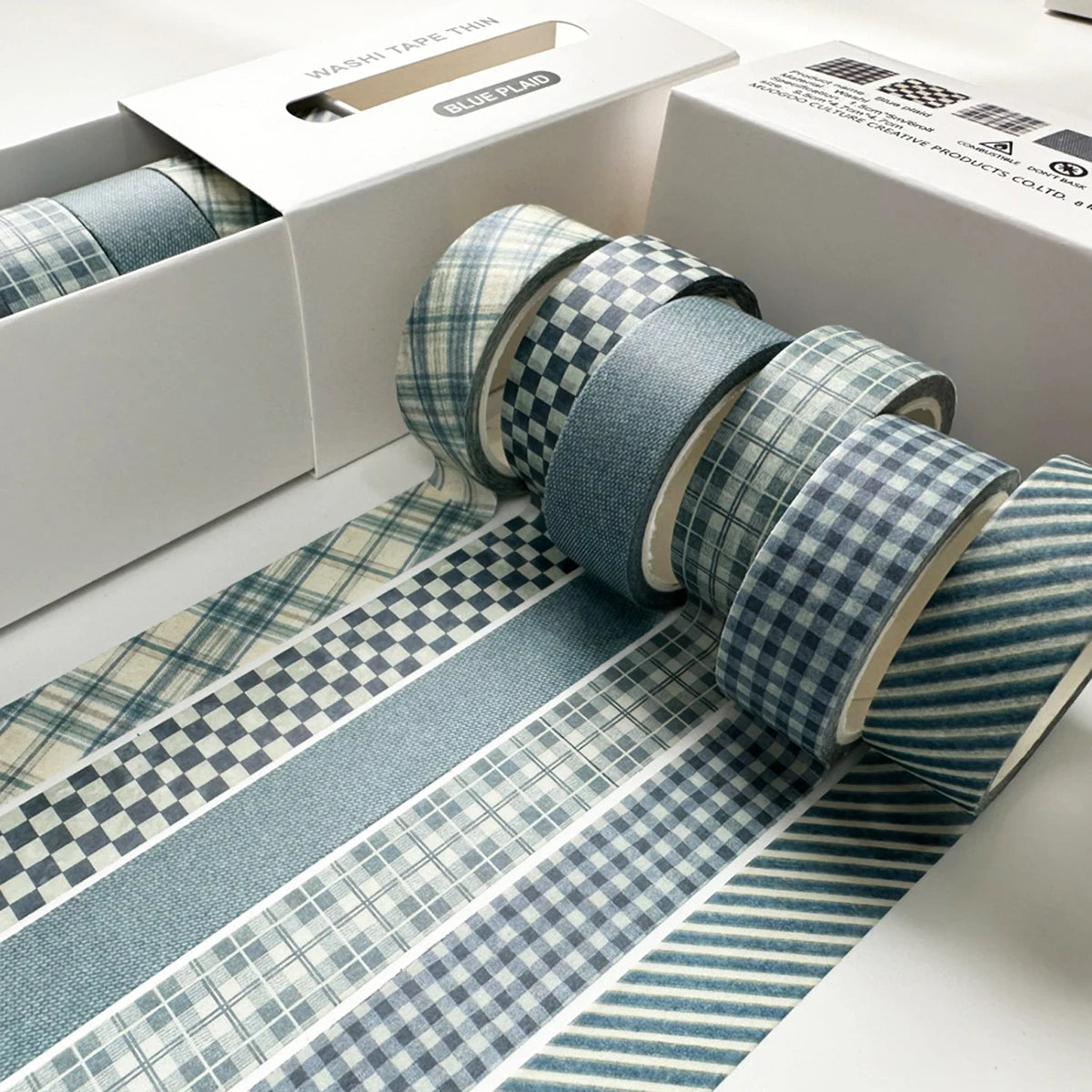 A set of six rolls of blue and white plaid and polka dot washi tape on a white box.