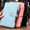 A stack of three A5 retro leather notebooks in light blue, pink, and black with gold accents.