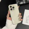A hand holds a light beige iPhone with a clear case and multiple camera lenses against a dark background.