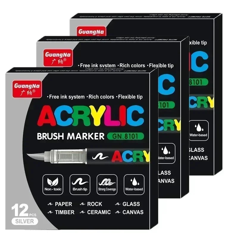 A set of twelve silver acrylic brush markers with various tips and colors displayed in black packaging.