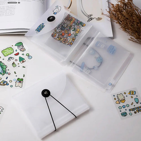 A clear plastic storage book containing various stickers and documents is shown next to a notebook.