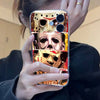 A close-up photo of a hand holding an iPhone case featuring multiple images of Michael Myers masks.