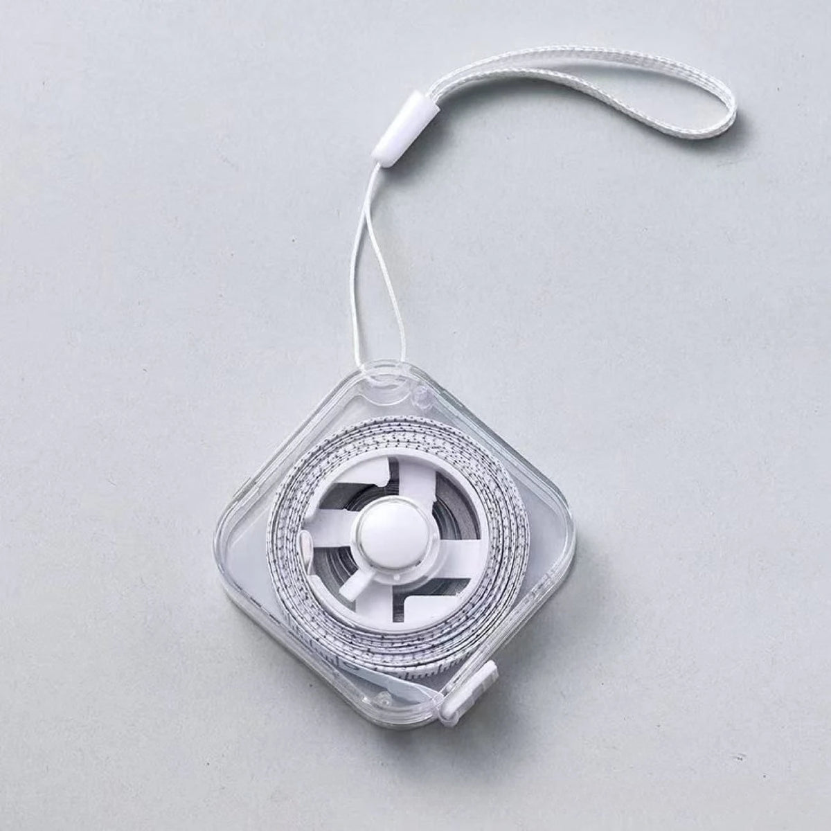 A clear plastic compact retractable measuring tape with a white cord and lock mechanism.