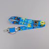 Blue lanyard featuring a repeating pattern of cute cats, palm leaves, and camera icons.